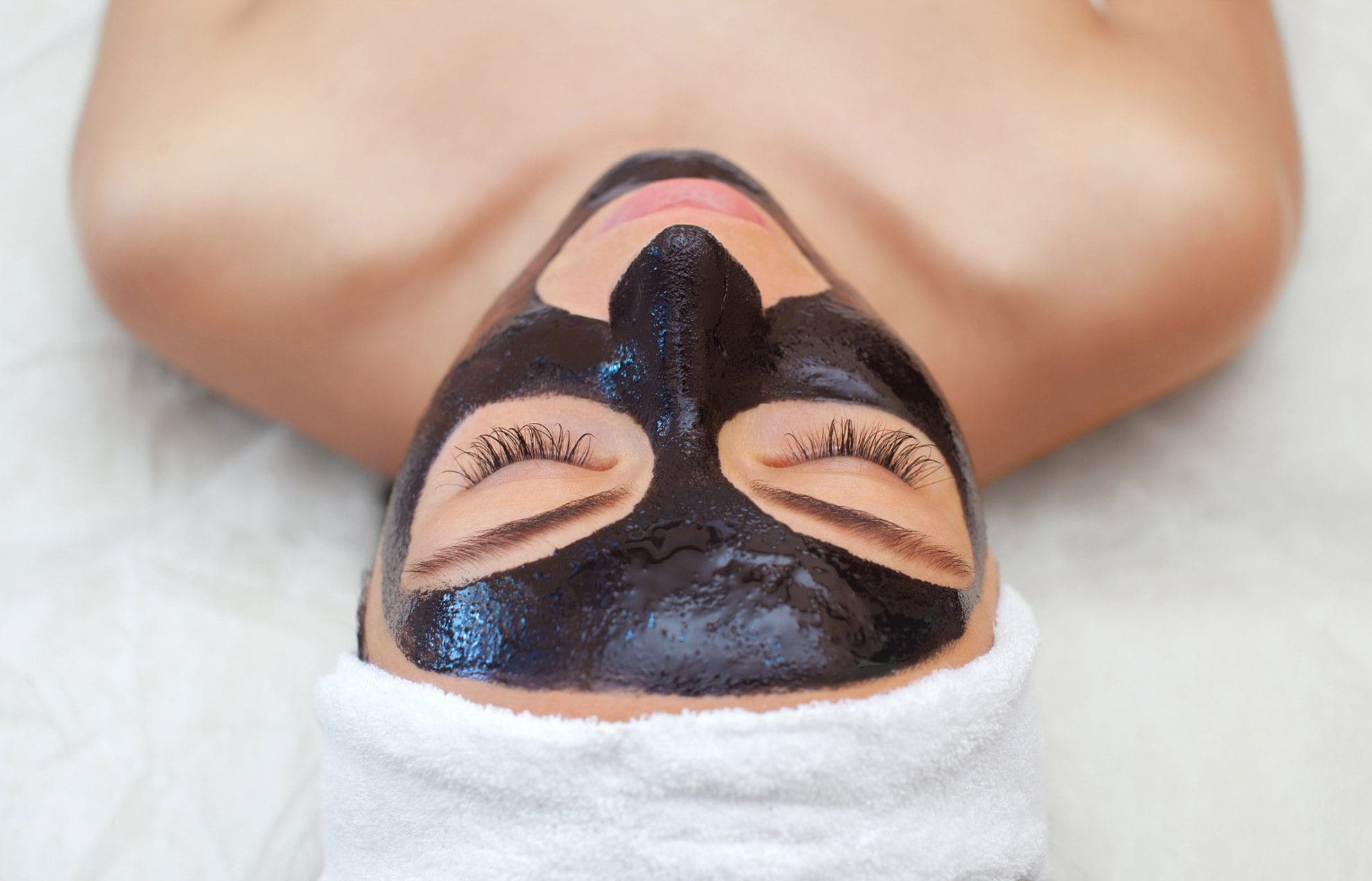 Woman lying down with a carbon mask before carbon facial with PicoLazer